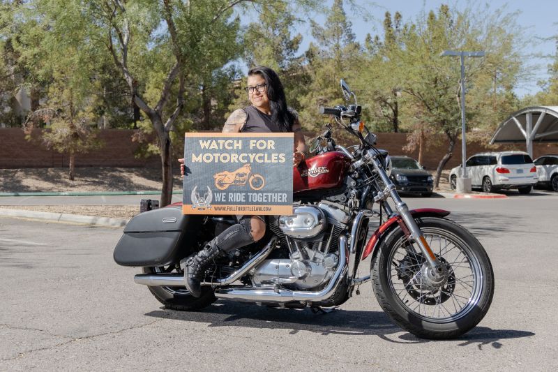 A female rider poses with her Watch For Motorcycles yard sign